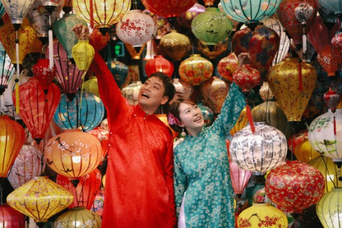 Couple in traditional clothing among colorful lanterns