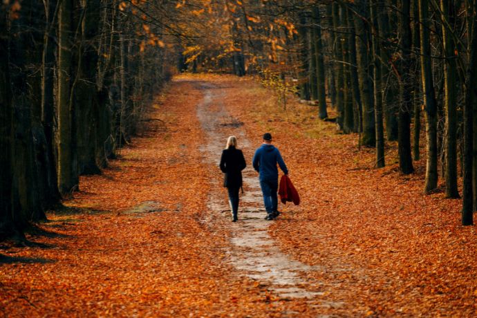Couple walking on autumn path covered in leaves