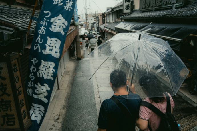 Couple walks down rainy street with umbrellas