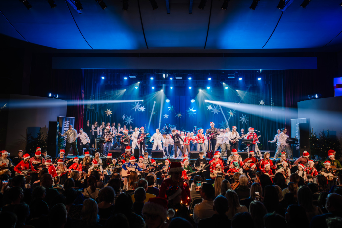 The joyful atmosphere of a seasonal show with a large ensemble of performers and an audience. The joyful atmosphere of a seasonal show with a large ensemble of performers and an audience.