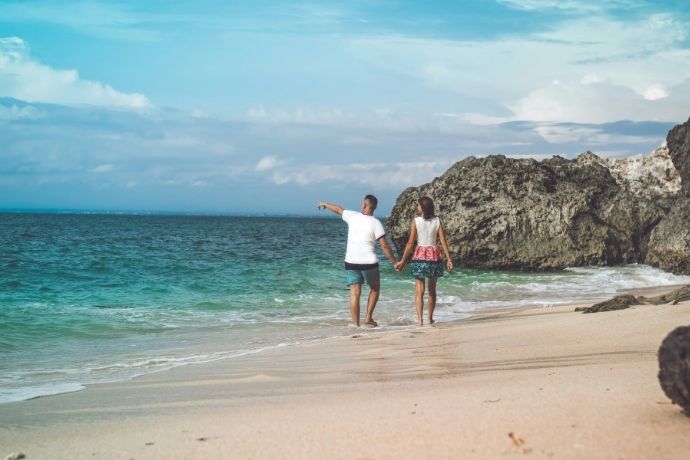 Happy young honeymoon couple walking on the beach