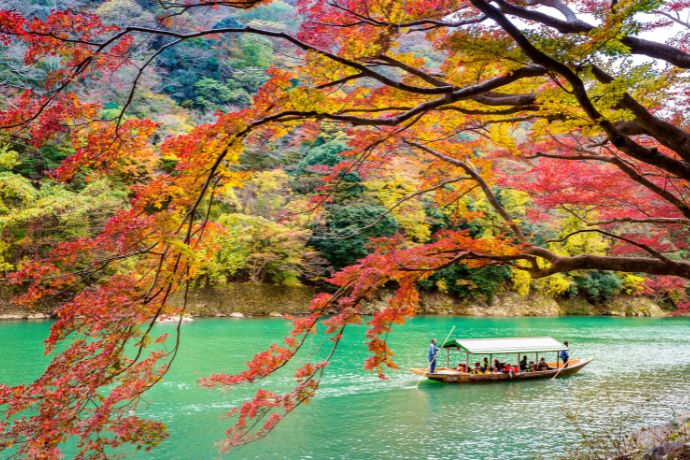 Boatman punting the boat at river. Arashiyama in autumn season along the river in kyoto, japan.