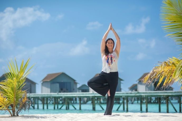 Woman practicing yoga tree pose on a tropical beach